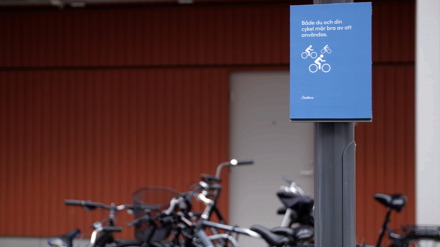Bild på en skylt i ett av våra bostadsrområden med nyproducerade bostäder i stockholm, göteborg eller malmö. skylten knuffar till hållbara val genom nudging - i det här fallet att ta cykeln
